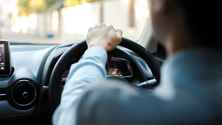 Close-up of a person driving in a car on the road